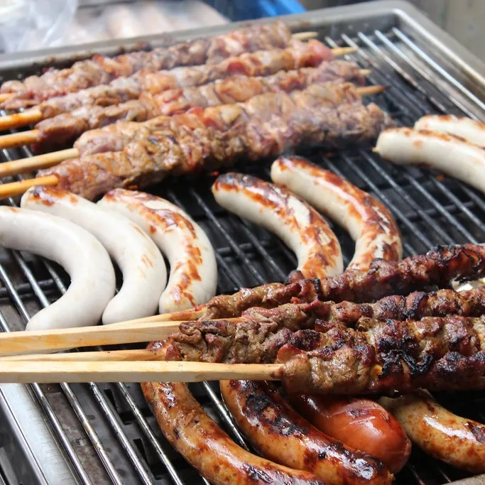 Würste und Fleischspiesse auf einem Grill.