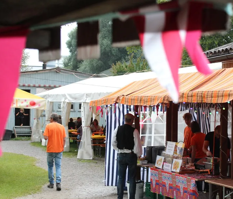 Bunt geschmücktes Festgelände mit Marktständen und Zelten.