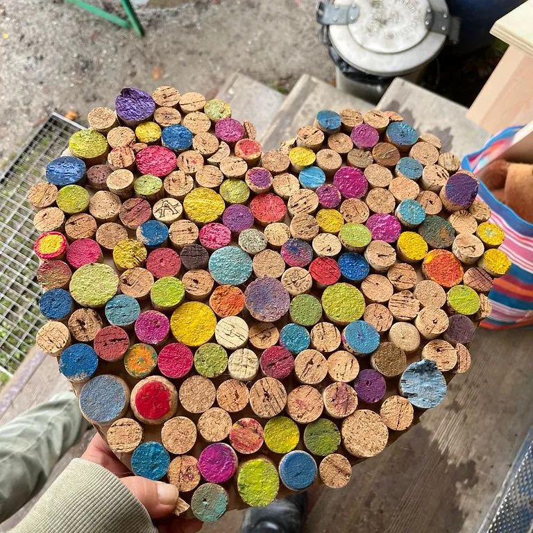 Ein bunt gestaltetes Werk aus Korken wird in den Händen gehalten.