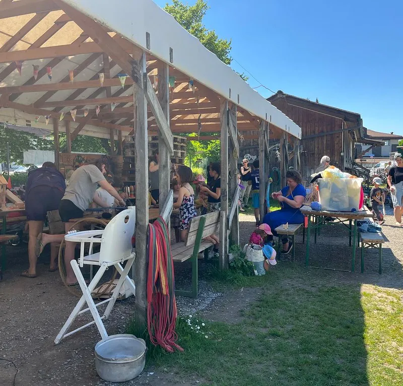 Sommerfest unter einem offenen Holzdach mit Familien und Spielangeboten.
